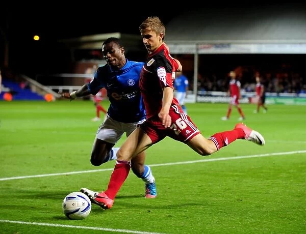 Bristol City's Joe Bryan Outmaneuvers Gabriel Zakuani of Peterborough United in Championship Clash