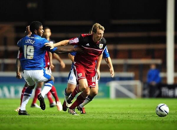 Bristol City's Martyn Woolford Outmaneuvers Peterborough United's Mark Little in Championship Clash
