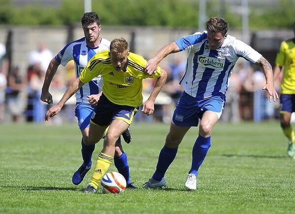Bristol City's Rhys Jordan Fights for Possession Against Clevedon Town Defense in Pre-Season Friendly