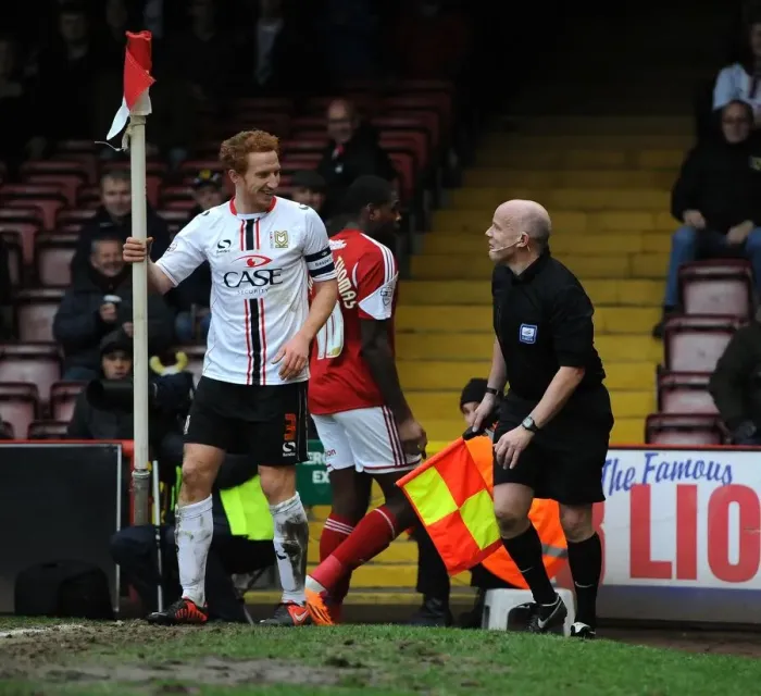 Framed Print : Dramatic Moment: Dean Lewington Slides Out MK Dons Teammate into Linesman during Bristol City vs MK Dons Match