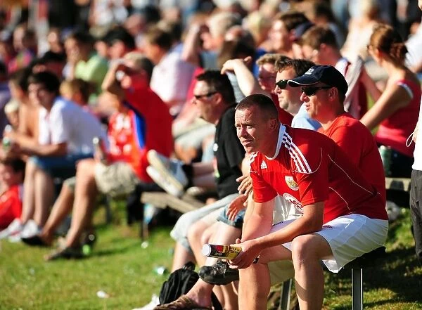 Fans from both teams sit in the sun to watch the game