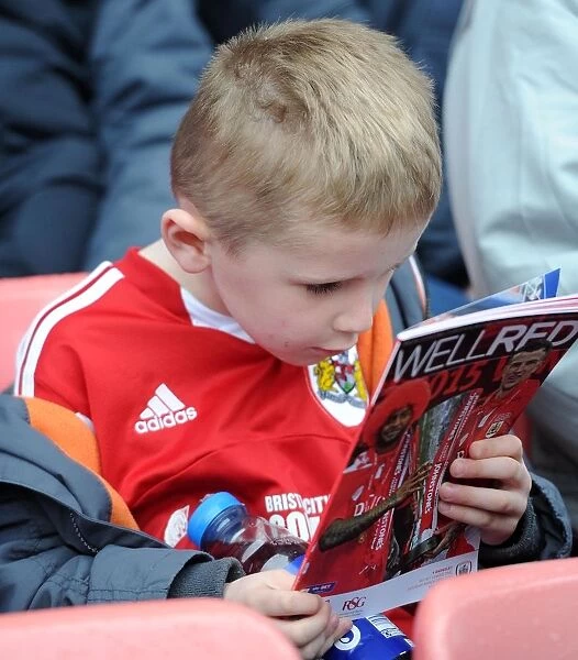 Young Fan Examines Match Program at Bristol City vs Barnsley Game, March 2015